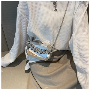 Detail of silver acrylic geometric box bag with chunky chain on a female model