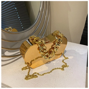 Macro shot of heart-shaped gold metal handbag with textured chain and mirror finish