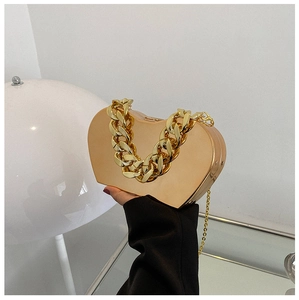 Detail of heart shaped gold metal clutch bag with chunky chain handle and mirror finish
