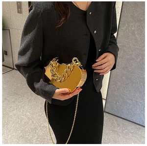 Macro shot of gold heart-shaped metal clutch bag with glossy finish and thick chain