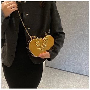 Golden heart-shaped metal evening bag with chunky chain strap and polished mirror finish