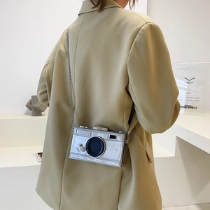 Silver camera shaped crossbody bag with metallic finish and metal chain strap for women