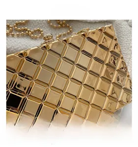 Detailed close-up of shiny gold geometric textured evening bag with luxury bead chain