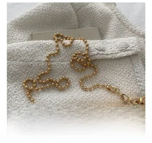 Detail of golden bead chain strap with lobster clasp on a clear quilted acrylic bag