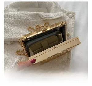 Interior detail of a gold quilted acrylic box clutch showing space for phone and makeup