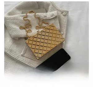 Close-up of gold lattice box clutch bag with elegant round bead chain next to a phone