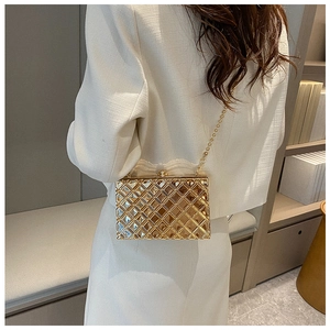Detail shot of a golden geometric hollow-out evening clutch bag with chic bead chain strap