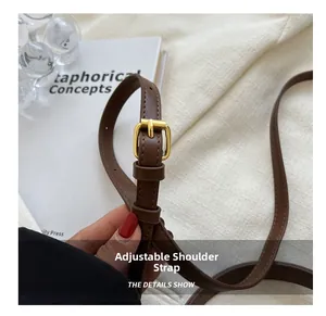 Detail of adjustable brown leather shoulder strap with a gold metal rectangular buckle