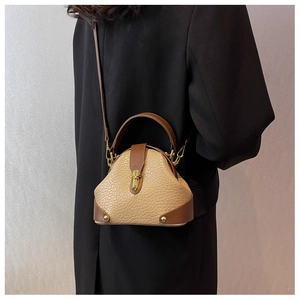 Close-up of beige pebble leather bag with brown trim and shiny gold metal buckle closure
