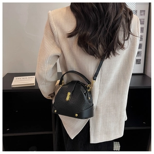 Detail of black litchi texture leather doctor bag with gold hardware and top handle