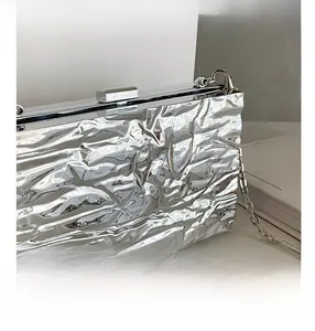 Detail shot of silver metallic evening bag with wrinkled texture and chain strap