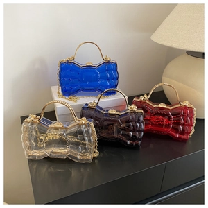 Détail de quatre sacs bandoulière en acrylique colorés avec chaînes dorées