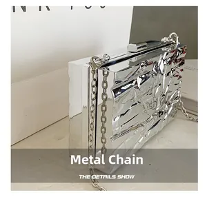 Detail of silver metallic box bag featuring crinkle texture and polished hardware chain