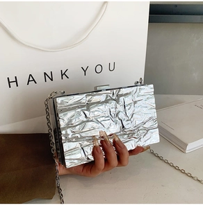 Detailed view of silver crinkled texture clutch with metallic finish and delicate chain