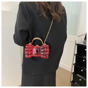 Détail de la pochette rouge en nœud avec pierre précieuse et anse dorée diamantée