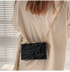 Detail of black acrylic crossbody bag with rock texture and gold metal chain
