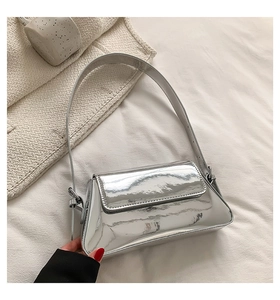 Detailed view of silver mirror finish underarm bag with adjustable buckled strap