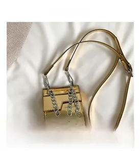 Détail du mini sac carré doré à effet miroir avec grosse chaîne argentée et boucle métal