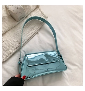 Detail of light blue patent leather shoulder bag with glossy finish on white fabric
