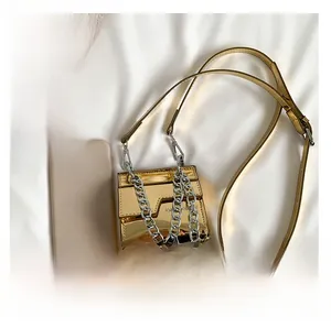 Détail du petit sac carré en cuir verni doré avec poignée en grosse chaîne argentée