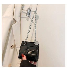 Détail du mini sac carré en cuir verni noir avec chaîne argentée et lettrage logo