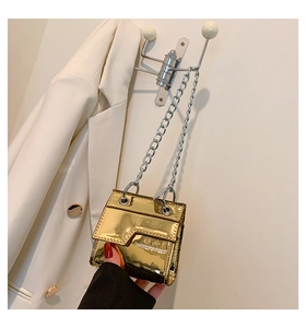 Détail du mini sac doré métallisé avec chaîne, finition miroir et texte mode