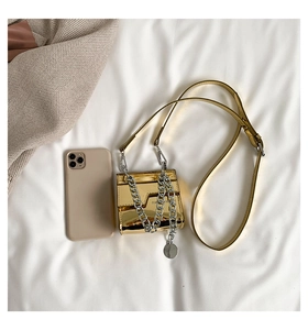 Vue de dessus d'un mini sac en cuir verni doré brillant avec chaîne argentée et un smartphone