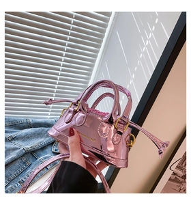 Detail of pink metallic mini bag with top handles and gold 'FASHION & BAGS' text