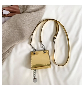 Détail d'un mini sac carré doré effet miroir avec fine bandoulière et breloques chaîne