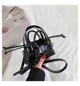 Close-up of black patent leather mini bag with gold ring and FASHION & BAGS logo
