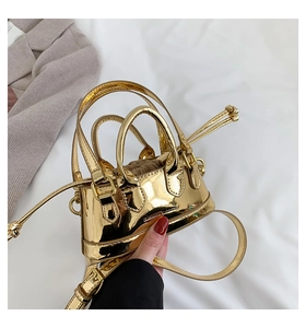 Detail of mini gold shiny patent leather shell bag with adjustable strap and drawstring lining