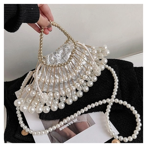 Detail of evening handbag with white pearls, gold cage structure and silver inner pouch