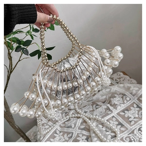 Close-up of pearl beaded handbag featuring gold metal frame and silver inner pouch