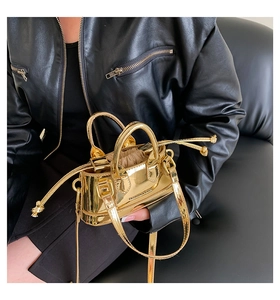 Detail of mini gold metallic bag with drawstring interior and crossbody strap