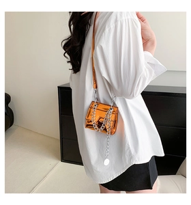 Détail de la finition en cuir verni orange brillant et de la chaîne argentée du sac carré