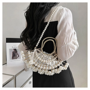 Detailed close-up of a vintage fan-shaped evening bag with pearls and a gold metal frame