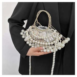 Detailed view of fan-shaped evening bag with white pearls and gold metal frame