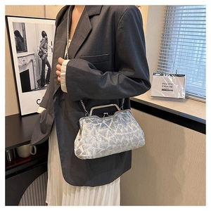 Silver iridescent sequin clutch bag shown on shoulder with metal chain and vintage clasp