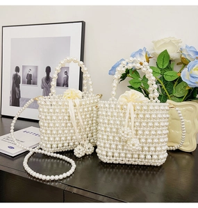 Detail of woven faux pearl bucket bag with silk drawstring liner and long chain strap