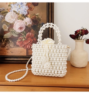 Detail of woven pearl handbag featuring cream satin drawstring lining and floral accent