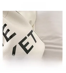 Detail of white lychee grain leather bucket bag with black KET lettering and fine stitching
