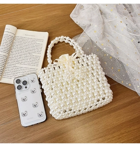 Detailed view of woven pearl handbag with satin drawstring pouch and pearl handle