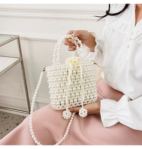 Detail of handmade pearl woven handbag with satin drawstring pouch and flower charms