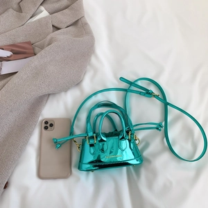 Mini metallic green patent leather crossbody bag with drawstring interior on grey blazer