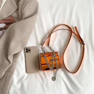 Mini sac carré orange verni avec chaîne argentée et bandoulière, vue de dessus élégante