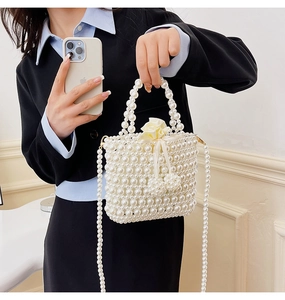 Detail of woven pearl handbag featuring cream silk flower decoration and beaded strap