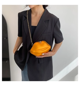 Sac à bandoulière chic en forme de lèvres doré orangé avec chaîne dorée porté par un mannequin