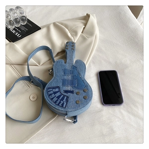 Détail du sac à bandoulière en denim en forme de guitare avec écusson sur un blazer
