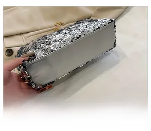 Close-up of silver sequin clutch bag showing reinforced base and gold chain strap
