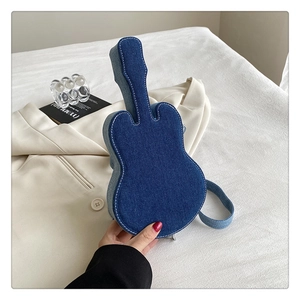 Gros plan d'un sac en denim en forme de guitare avec surpiqûres blanches et bandoulière